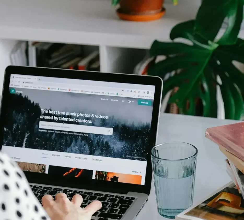 A woman working from home on her laptop surrounded by plants and books for a cozy office feel.